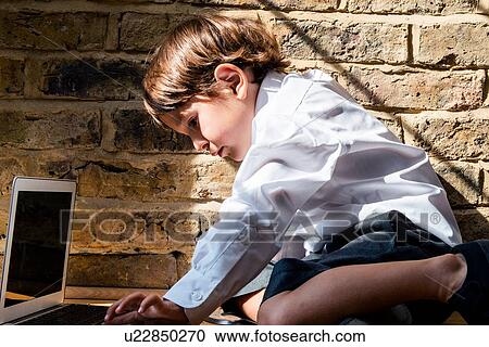 Boy in school uniform using laptop at home View Large Photo Image Stock Image - Boy in school uniform using laptop at home. Fotosearch