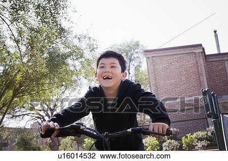 Stock Image - Boy riding bicycle in park. Fotosearch
