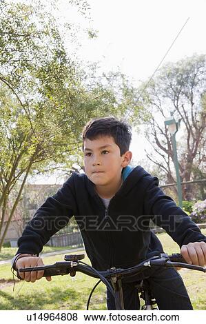 Boy riding bicycle in park View Large Photo Image Stock Photo - Boy riding bicycle in park. Fotosearch