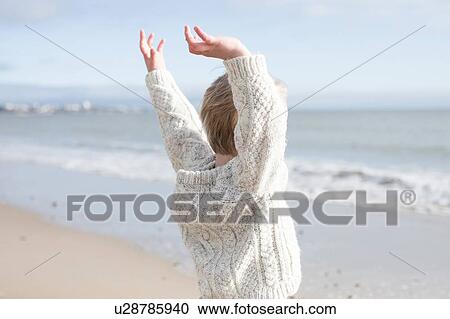 Stock Image - Boy stretching arms on beach. Fotosearch
