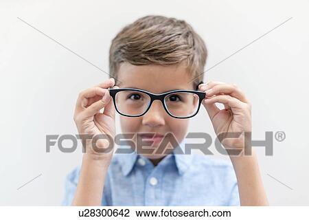 Stock Image - Boy wearing glasses, studio shot.. Fotosearch