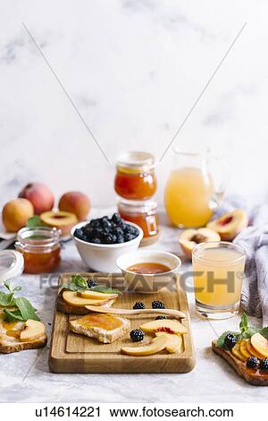 Stock Image - Breakfast spread with blackberries, peaches, toast and apricot jam. Fotosearch