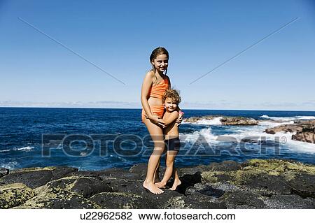 Brother and sister embracing on rocks by sea View Large Photo Image Stock Image - Brother and sister embracing on rocks by sea. Fotosearch