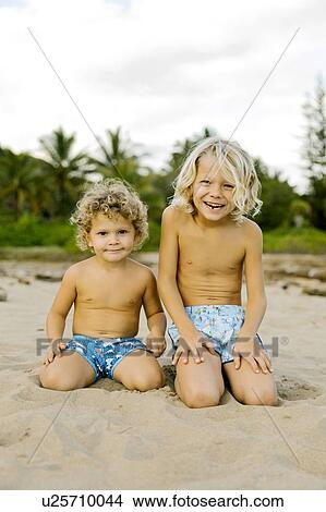 Picture - Brothers kneeling on beach. Fotosearch