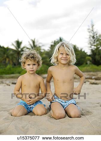 Brothers kneeling on beach View Large Photo Image Stock Photo - Brothers kneeling on beach. Fotosearch