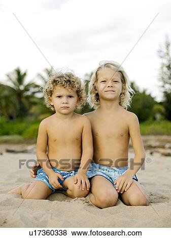 Brothers kneeling on beach View Large Photo Image Stock Photo - Brothers kneeling on beach. Fotosearch
