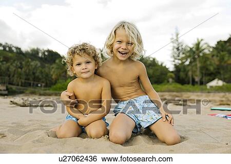 Stock Photograph - Brothers kneeling on beach. Fotosearch