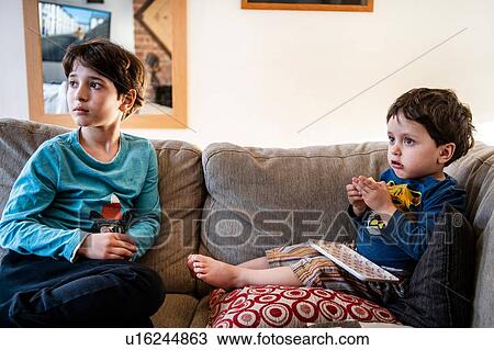 Stock Image - Brothers looking up in disbelief on sofa. Fotosearch