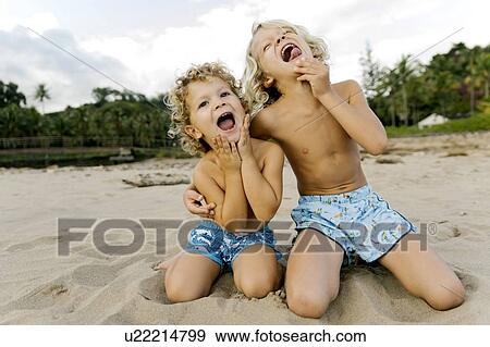Brothers making faces on beach View Large Photo Image Stock Photo - Brothers making faces on beach. Fotosearch