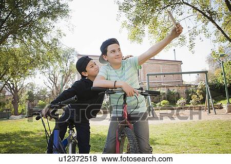 Stock Photo - Brothers taking selfie on bicycles. Fotosearch