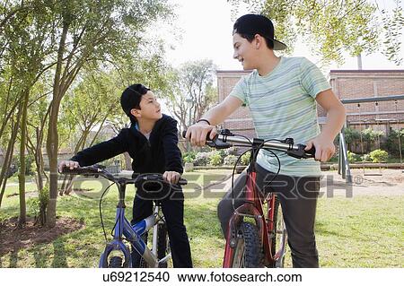 Brothers with bicycles in park View Large Photo Image Stock Image - Brothers with bicycles in park. Fotosearch