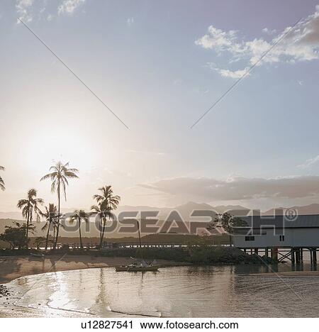 Stock Image - Building by beach at sunset in Port Douglas, Australia. Fotosearch