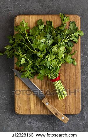 Stock Image - Bunch of parsley and knife on cutting board. Fotosearch