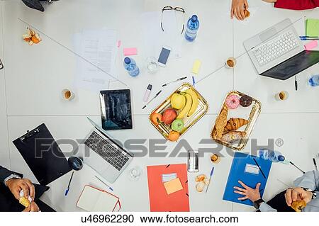 Stock Image - Business partners having tea break at meeting in office. Fotosearch