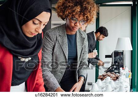 Stock Image - Business partners having tea break in office. Fotosearch