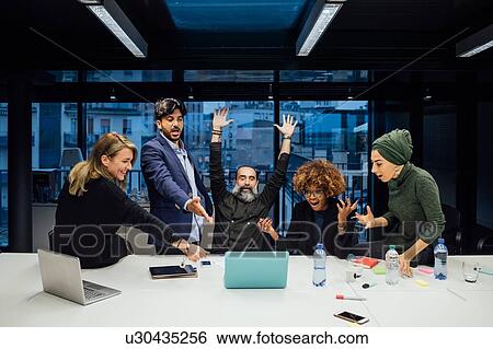 Stock Photograph - Business partners rejoicing in office. Fotosearch