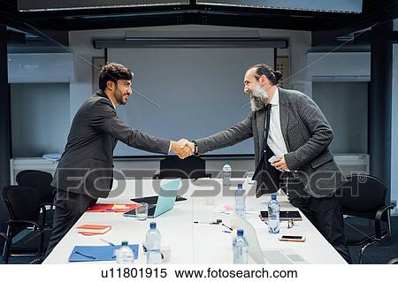 Stock Photography - Business partners shaking hands at meeting in office. Fotosearch