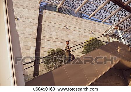 Businessman ascending escalator of office building, Milano, Lombardia, Italy View Large Photo Image Stock Image - Businessman ascending escalator of office building, Milano, Lombardia, Italy. Fotosearch