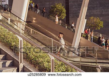 Stock Photo - Businessman ascending escalator of office building, Milano, Lombardia, Italy. Fotosearch
