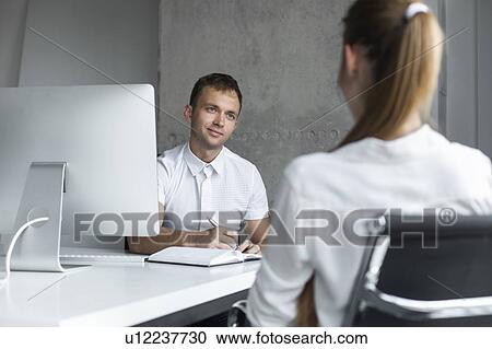 Businessman conducting job interview with young woman View Large Photo Image Stock Image - Businessman conducting job interview with young woman. Fotosearch