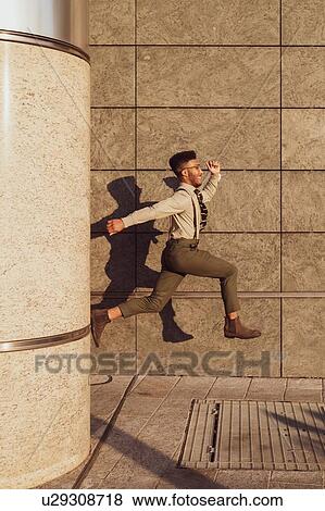 Stock Photo - Businessman jumping past concrete wall, Milano, Lombardia, Italy. Fotosearch