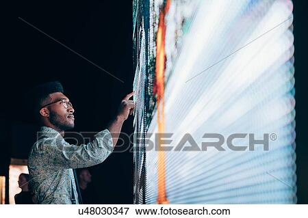 Stock Photo - Businessman pointing at digital information board. Fotosearch
