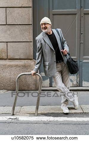 Stock Photography - Businessman resting against bicycle frame, Milan, Lombardia, Italy. Fotosearch