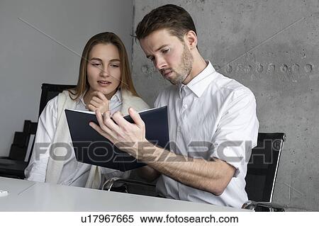 Businessman showing notebook to colleague View Large Photo Image Stock Photography - Businessman showing notebook to colleague. Fotosearch