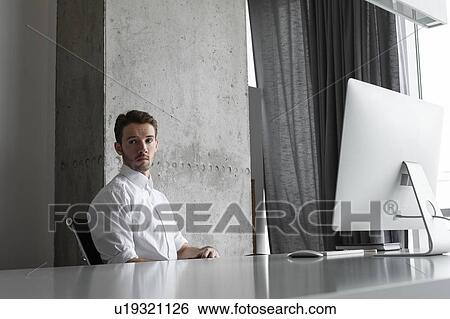 Stock Photograph - Businessman sitting at desk. Fotosearch