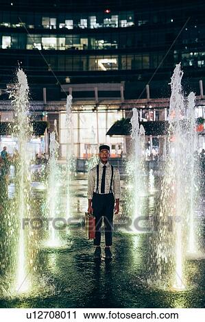 Stock Image - Businessman standing in between fountain square, Milano, Lombardia, Italy. Fotosearch