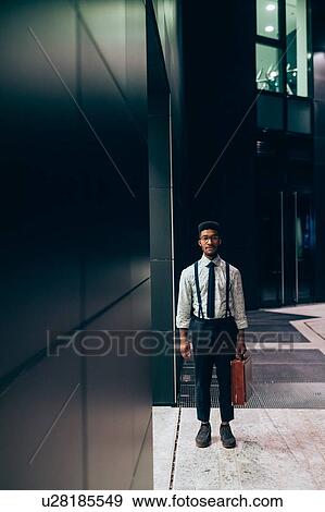 Stock Photo - Businessman standing in front of office building, Milano, Lombardia, Italy. Fotosearch
