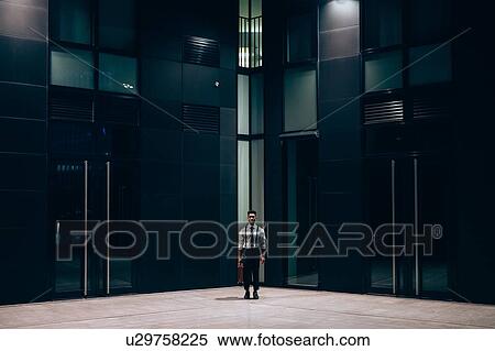 Stock Photography - Businessman standing in front of office building, Milano, Lombardia, Italy. Fotosearch
