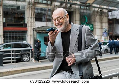 Businessman talking into smartphone on pavement, Milan, Lombardia, Italy View Large Photo Image Stock Photography - Businessman talking into smartphone on pavement, Milan, Lombardia, Italy. Fotosearch