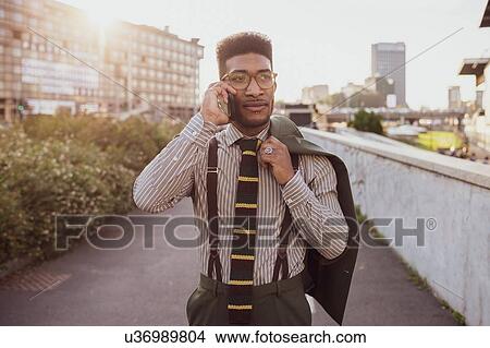 Picture - Businessman talking on smartphone and walking in city, Milano, Lombardia, Italy. Fotosearch