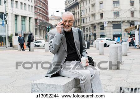Businessman talking on smartphone in square, Milan, Lombardia, Italy View Large Photo Image Picture - Businessman talking on smartphone in square, Milan, Lombardia, Italy. Fotosearch