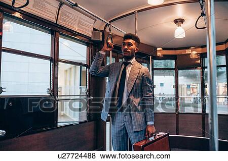 Stock Photo - Businessman travelling on tram in city. Fotosearch