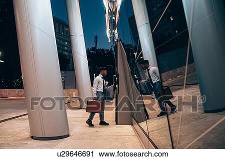 Stock Image - Businessman using access control panel at entrance of hotel building. Fotosearch