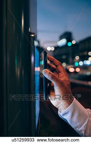Stock Image - Businessman using digital information system at bus stop. Fotosearch