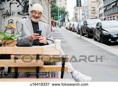 Stock Photo - Businessman using smartphone at cafe, Milan, Lombardia, Italy. Fotosearch