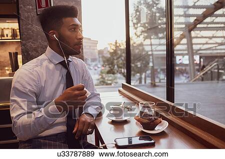 Stock Photo - Businessman using smartphone at tea time in cafe. Fotosearch