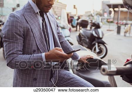 Businessman using smartphone by motorcycle View Large Photo Image Stock Photo - Businessman using smartphone by motorcycle. Fotosearch