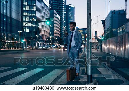 Businessman using smartphone by pedestrian crossing, Milano, Lombardia, Italy View Large Photo Image Stock Photograph - Businessman using smartphone by pedestrian crossing, Milano, Lombardia, Italy. Fotosearch