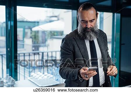 Businessman using smartphone in office View Large Photo Image Stock Photograph - Businessman using smartphone in office. Fotosearch