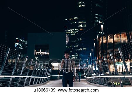 Stock Photo - Businessman using smartphone on bridge, Milano, Lombardia, Italy. Fotosearch