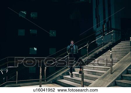 Stock Image - Businessman using smartphone on stairs of office building. Fotosearch