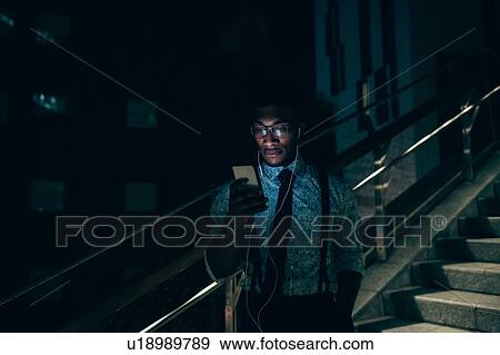 Businessman using smartphone on stairs of office building View Large Photo Image Stock Photo - Businessman using smartphone on stairs of office building. Fotosearch