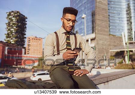 Businessman using smartphone on pavement, Milano, Lombardia, Italy View Large Photo Image Stock Photo - Businessman using smartphone on pavement, Milano, Lombardia, Italy. Fotosearch