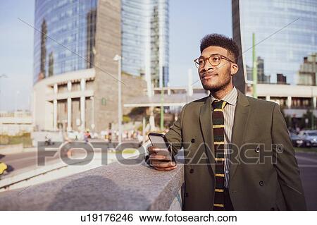 Businessman using smartphone on pavement, Milano, Lombardia, Italy View Large Photo Image Stock Photograph - Businessman using smartphone on pavement, Milano, Lombardia, Italy. Fotosearch