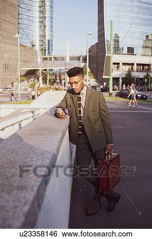 Businessman using smartphone on pavement, Milano, Lombardia, Italy View Large Photo Image Stock Photograph - Businessman using smartphone on pavement, Milano, Lombardia, Italy. Fotosearch