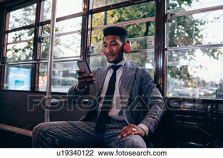Businessman using smartphone on tram in city View Large Photo Image Stock Image - Businessman using smartphone on tram in city. Fotosearch